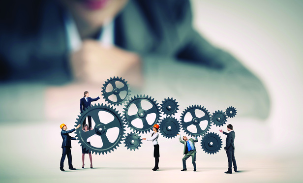 Businesswoman looking at team of businesspeople in miniature